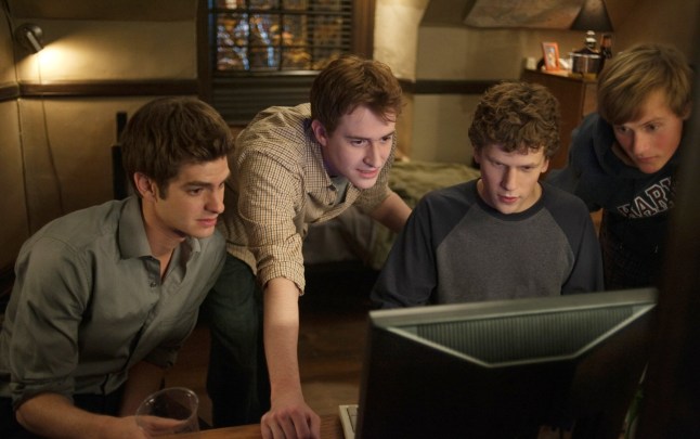 THE SOCIAL NETWORK, Andrew Garfield (left), Joseph Mazzello (left of center), Jesse Eisenberg (second from right) look at computer in scene from The Social Network - 2010