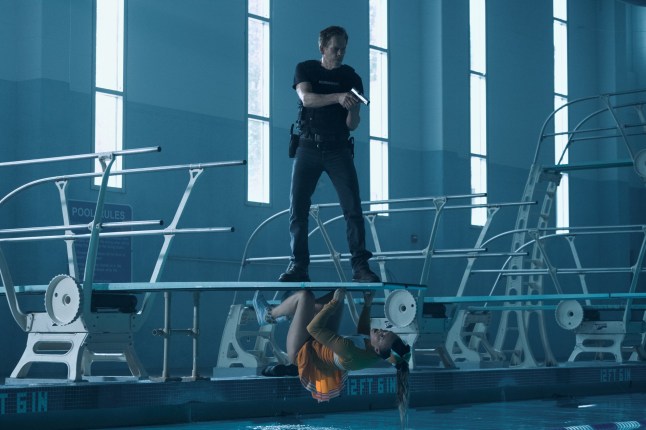 Kevin Bacon as Hub Halloran in The Bondsman. He is standing on a swimming pool diving board pointing a gun