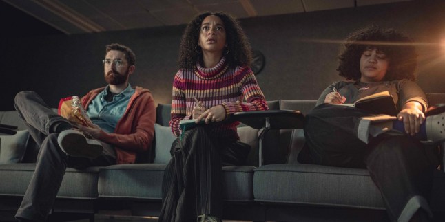 three people sitting on chairs watching tv