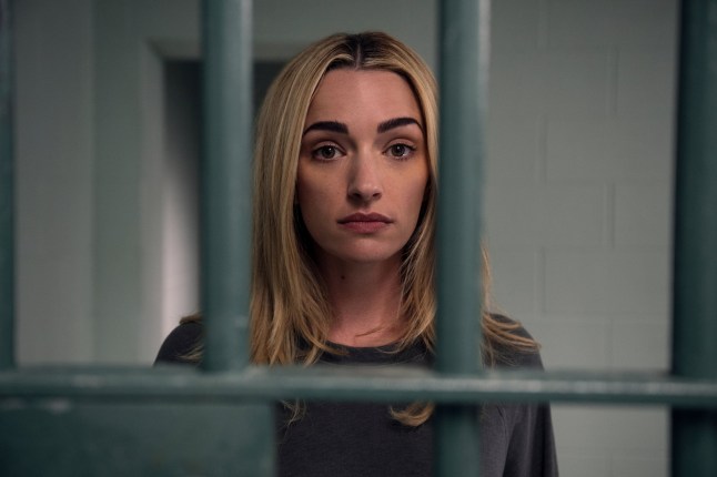 Brianne Howey as Georgia Miller stood behind prison bars