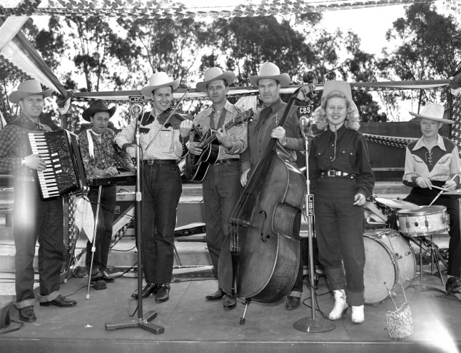 Cowboy musicians, Hank Caldwell (with large bass fiddle) and The Saddle Kings, with vocalist Betsy Gay (standing at right). April 27, 1952 in black and white